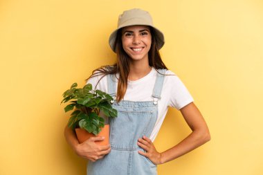 hispanic woman smiling happily with a hand on hip and confident. gardering concept