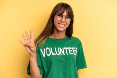 pretty woman smiling and looking friendly, showing number four. volunteer and donation concept