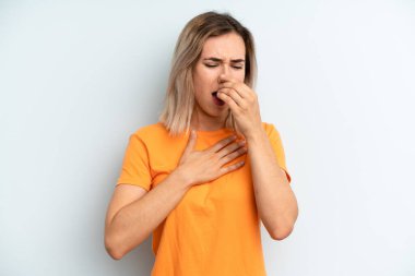 young adult pretty woman feeling ill with a sore throat and flu symptoms, coughing with mouth covered