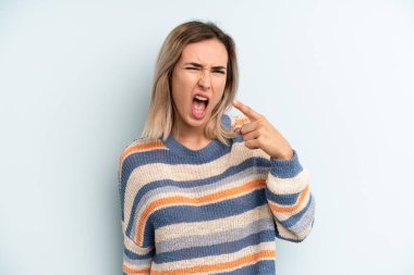 young adult pretty woman pointing at camera with an angry aggressive expression looking like a furious, crazy boss