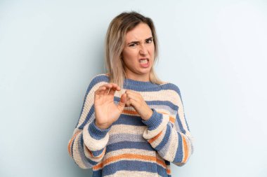 young adult pretty woman feeling disgusted and nauseous, backing away from something nasty, smelly or stinky, saying yuck