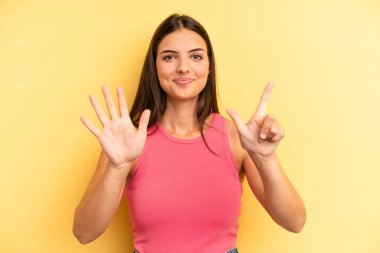 Genç ve güzel bir kadın gülümsüyor ve arkadaş canlısı görünüyor, 7 ya da 7 numarayı gösteriyor, eli önde, geriye doğru sayıyor.