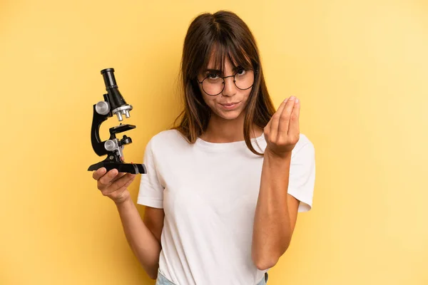 hispanic woman making capice or money gesture, telling you to pay. scients student concept