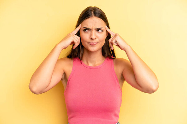 young adult pretty woman feeling confused or doubting, concentrating on an idea, thinking hard, looking to copy space on side