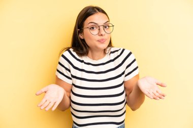 young adult pretty woman feeling clueless and confused, having no idea, absolutely puzzled with a dumb or foolish look