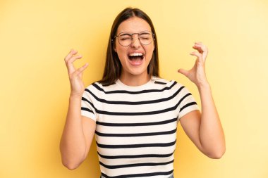 Genç ve güzel bir kadın öfkeyle bağırıyor, strese giriyor ve ellerini havaya kaldırıp 