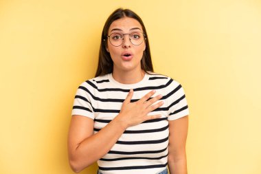 Genç ve güzel bir kadın şok olmuş ve şaşırmış hissediyor, gülümsüyor, el ele tutuşuyor, mutlu oluyor ya da minnettarlık gösteriyor.