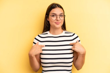 Genç ve güzel bir kadın gururlu, pozitif ve iki eliyle göğsünü gösteren.