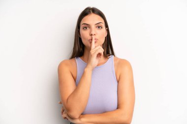 Genç ve güzel bir kadın ciddi görünüyor ve parmaklarını dudaklarına bastırıp sessizlik ya da sessizlik talep ediyor, sır saklıyor.