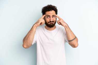Genç, sakallı bir adam konsantre olmuş ve bir fikir üzerinde kafa yoruyor. Bir soruna ya da soruna çözüm bulmayı hayal ediyor.