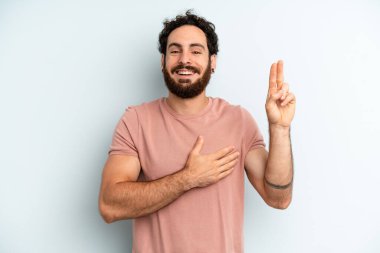 Genç, sakallı, mutlu, kendinden emin, güvenilir, gülümseyen ve zafer işareti gösteren bir adam.