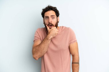 Ağzı ve gözleri açık, eli çenesinde genç, sakallı bir adam. Hoş olmayan bir şok geçiriyor.