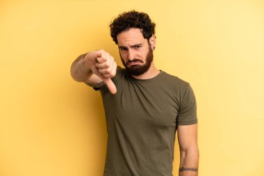 Genç, sakallı, sinirli, sinirli, hayal kırıklığına uğramış ya da hoşnutsuz bir genç. Ciddi bir bakışla reddediyor.