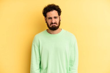 Genç, sakallı, üzgün ve mızmız bir adam. Mutsuz bir bakışla ağlıyor. Olumsuz ve hayal kırıklığına uğramış bir tavırla.