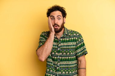 Genç, sakallı, şok olmuş ve ağzı açık bir şekilde yüz yüze inanamamaktan şaşkına dönmüş genç bir adam.
