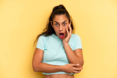 İspanyol güzel kadın şok ve inançsızlık içinde ağzı açık, elleri yanağında ve kolları çaprazlanmış, sersemlemiş ve şaşırmış hissediyor