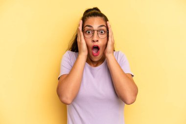 İspanyol güzel kadın hoş olmayan bir şekilde şok olmuş, korkmuş ya da endişeli görünüyor, ağzı sonuna kadar açık ve iki kulağını da elleriyle kapatıyor.