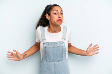 hispanic pretty woman feeling clueless and confused, having no idea, absolutely puzzled with a dumb or foolish look