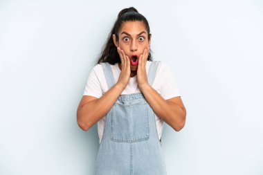 İspanyol güzel kadın şok olmuş ve korkmuş hissediyor, ağzı açık ve elleri yanaklarında korkmuş görünüyor.