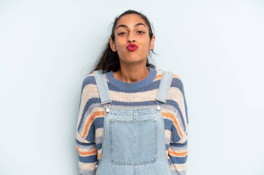 Tatlı, eğlenceli, mutlu, sevimli bir yüz ifadesiyle dudaklarını birbirine bastıran İspanyol güzeli bir kadın öpücük yolluyor.