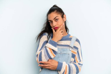 İspanyol güzel kadın ciddi, düşünceli ve güvensiz görünüyor, bir kolu çapraz ve çene üzerinde, seçenekleri tartıyor