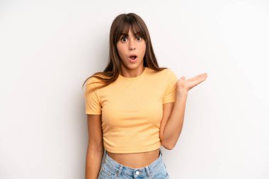 İspanyol güzel kadın şaşırmış ve şoka uğramış görünüyor, çenesi düşmüş, elinde açık bir elle bir nesne tutuyor.