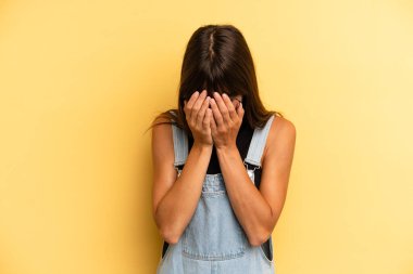 Hispanik güzel kadın üzgün, hayal kırıklığına uğramış, gergin ve depresif, iki eliyle yüzünü kaplayan, ağlayan