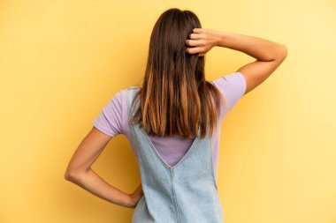 Hispanik güzel kadın düşünüyor ya da şüphe ediyor, kafasını kaşıyor, şaşkın ve şaşkın hissediyor, arkaya ya da arkaya bakıyor.