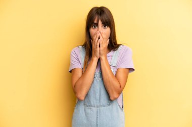Hispanik güzel kadın endişeli, üzgün ve korkmuş hissediyor, elleriyle ağzını kapatıyor, endişeli ve berbat görünüyor.