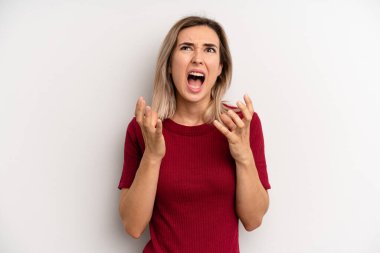 young adult blonde woman looking desperate and frustrated, stressed, unhappy and annoyed, shouting and screaming