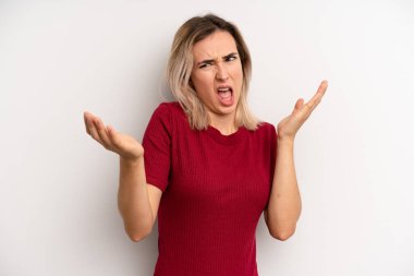 young adult blonde woman shrugging with a dumb, crazy, confused, puzzled expression, feeling annoyed and clueless