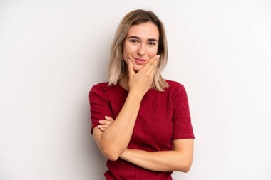 Genç, sarışın bir kadın ciddi, düşünceli ve güvensiz görünüyor. Bir kolu çapraz, eli çenesinde, seçenekleri tartıyor.