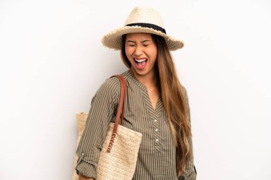 Asyalı genç bir kadın agresif bir şekilde bağırıyor, çok kızgın görünüyor. yaz ve şapka konsepti