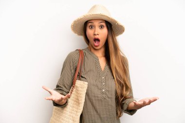 Asyalı genç bir kadın inanılmaz bir sürprizle şaşkına döndü ve hayrete düştü. yaz ve şapka konsepti