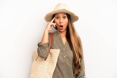 Asyalı genç kadın şaşırmış görünüyor, yeni bir düşünce, fikir ya da konsept fark ediyor. yaz ve şapka konsepti