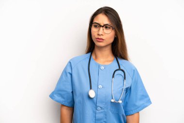 Asyalı genç bir kadın üzgün, üzgün ya da kızgın hissediyor ve yana bakıyor. hemşire ya da doktor konsepti