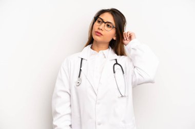 Asyalı genç kadın şaşkın ve kafası karışık, kaşınan bir kafa hissediyor. doktor konsepti