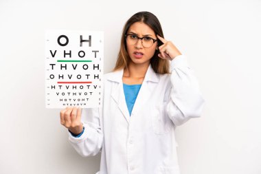 Asyalı genç bir kadın kafası karışık ve şaşkın hissediyor, senin deli olduğunu gösteriyor. optik görüş testi konsepti