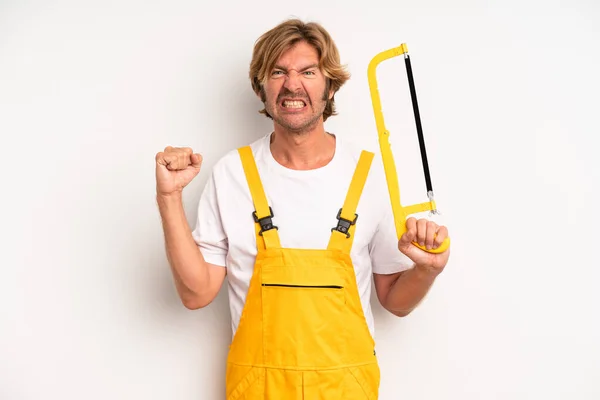 Adult Blond Man Shouting Aggressively Angry Expression Handyman Saw Concept — Stockfoto