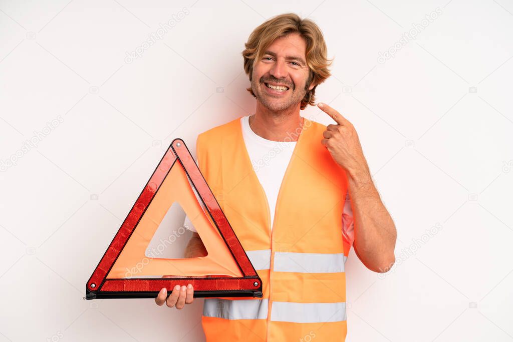adult blond man smiling confidently pointing to own broad smile. car emergency concept