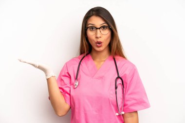 asian young woman looking surprised and shocked, with jaw dropped holding an object. veterinarian student concept