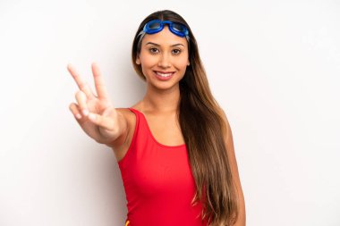 Asyalı genç kadın gülümsüyor ve mutlu görünüyor, zafer ya da barış işareti yapıyor. yüzücü kavramı