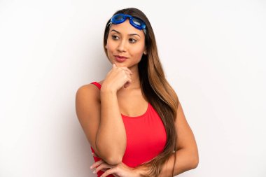 Asyalı genç bir kadın mutlu ve kendinden emin bir ifadeyle gülümsüyor, elleri çenesinde. yüzücü kavramı