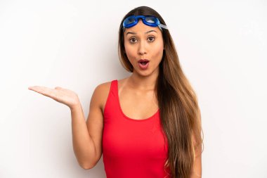 Asyalı genç kadın şaşırmış ve şok olmuş görünüyor. Çenesi düşmüş ve elinde bir nesne var. yüzücü kavramı