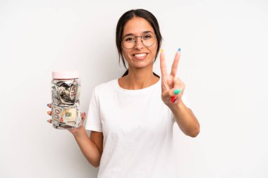 İspanyol güzel kadın gülümsüyor ve arkadaş canlısı görünüyor, ikinciyi gösteriyor. domuz kumbarası tasarruf kavramı