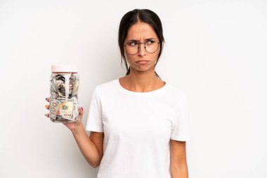 Hispanik güzel kadın üzgün, üzgün ya da kızgın hissediyor ve yana bakıyor. domuz kumbarası tasarruf kavramı