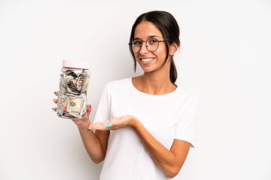 İspanyol güzel kadın neşeyle gülümsüyor, mutlu hissediyor ve bir konsept gösteriyor. domuz kumbarası tasarruf kavramı