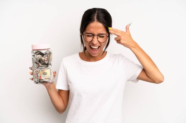 İspanyol güzel kadın mutsuz ve stresli görünüyor, intihar jesti silah işareti yapıyor. domuz kumbarası tasarruf kavramı