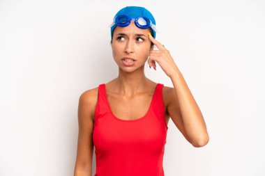 hispanic pretty woman feeling confused and puzzled, showing you are insane. swimmer concept
