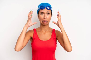 hispanic pretty woman screaming with hands up in the air. swimmer concept